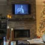 A fireplace with a surround made of GenStone faux stone, next to a Christmas tree, A great project for upgrading your living room before the holidays.