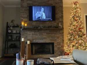 A fireplace with a surround made of GenStone faux stone, next to a Christmas tree,