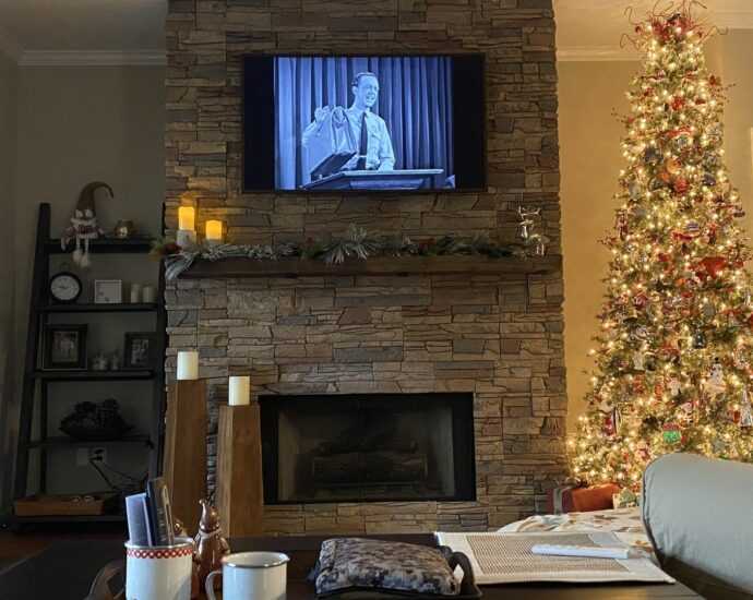 A fireplace with a surround made of GenStone faux stone, next to a Christmas tree, A great project for upgrading your living room before the holidays.